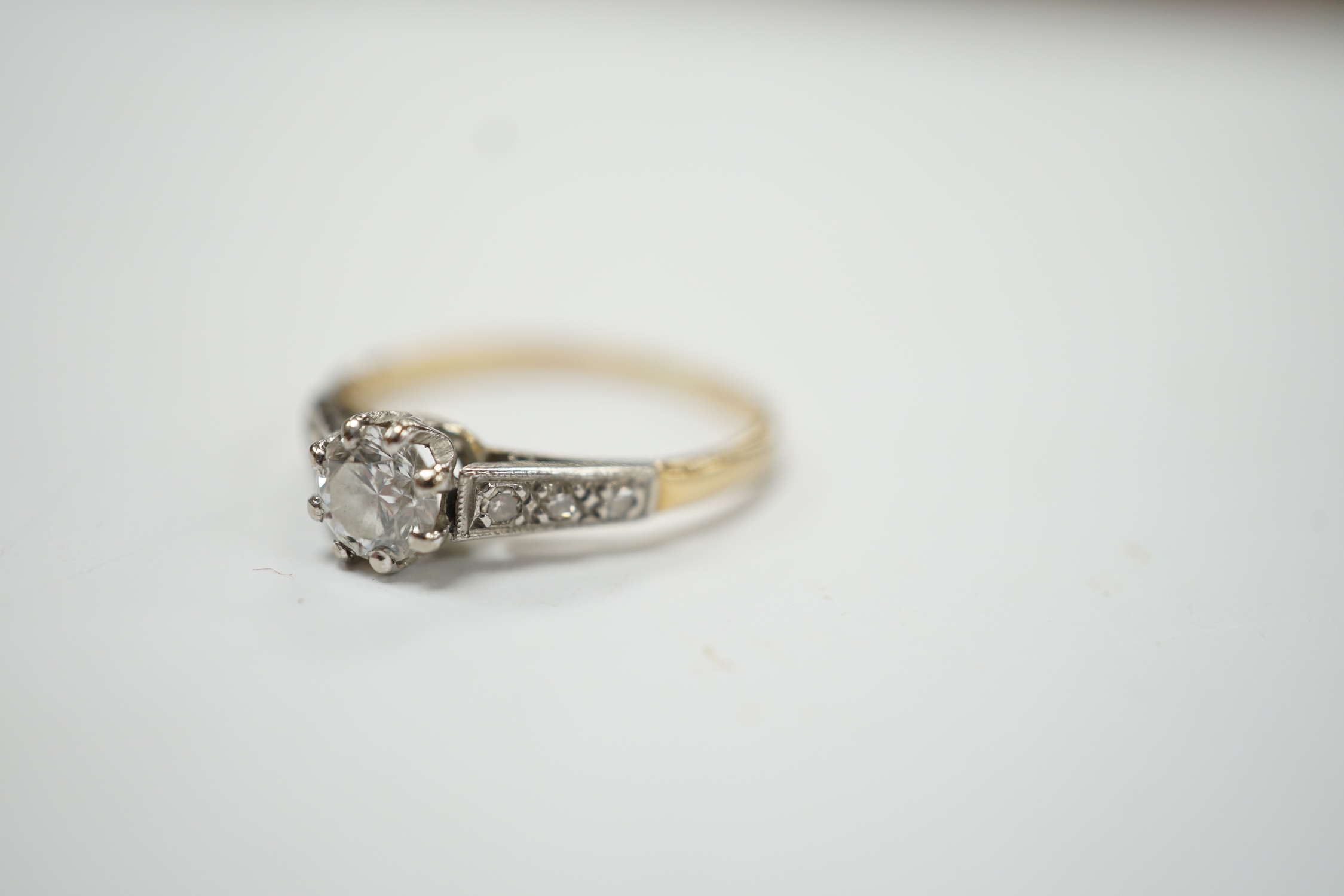 An early 20th century 18ct, plat. and single stone diamond set ring, with six stone diamond chip set shoulders, size O, gross weight 2.3 grams. Good condition.